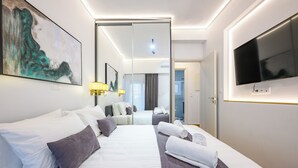 Habitación de hotel moderna con una cama grande, un televisor de pantalla plana y un cuadro en la pared.
