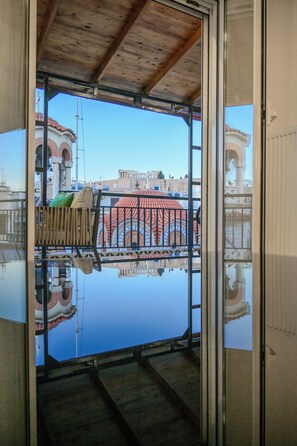 Ein Zimmer mit einem großen Glasfenster, das einen Gebäudebereich mit Bögen und einem roten Dach spiegelt.
