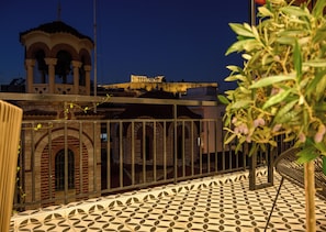 A courtyard with a tiled floor, a metal railing, and a building with arches in the background. - Acropolis Golden View Penthouse | 17 Dimitrakopoulou str 11742 Athens (Athens)