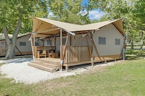 A wooden cabin with a porch, a table, and chairs, surrounded by trees.