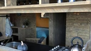 Una cocina con estufa a gas, hervidor y repisas con cristalería.