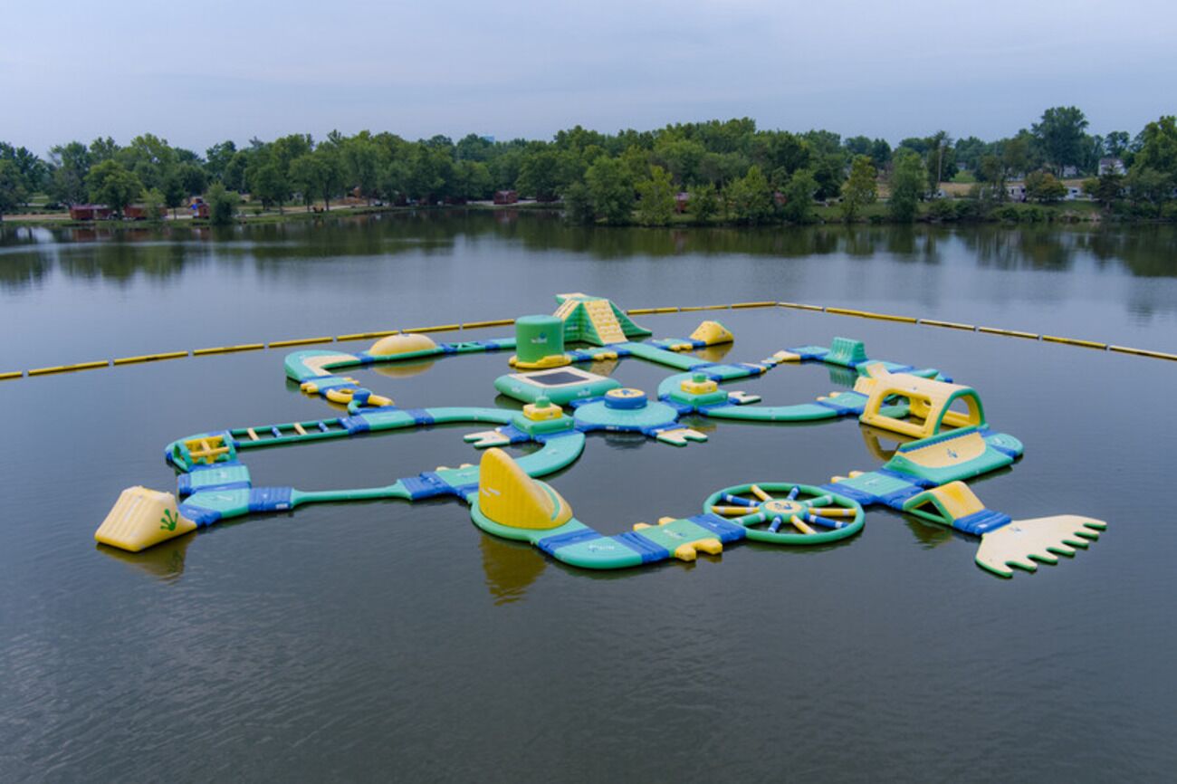 A water park with various play structures on a lake.