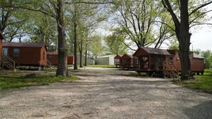 A campground with wooden cabins, a gravel path, and trees.