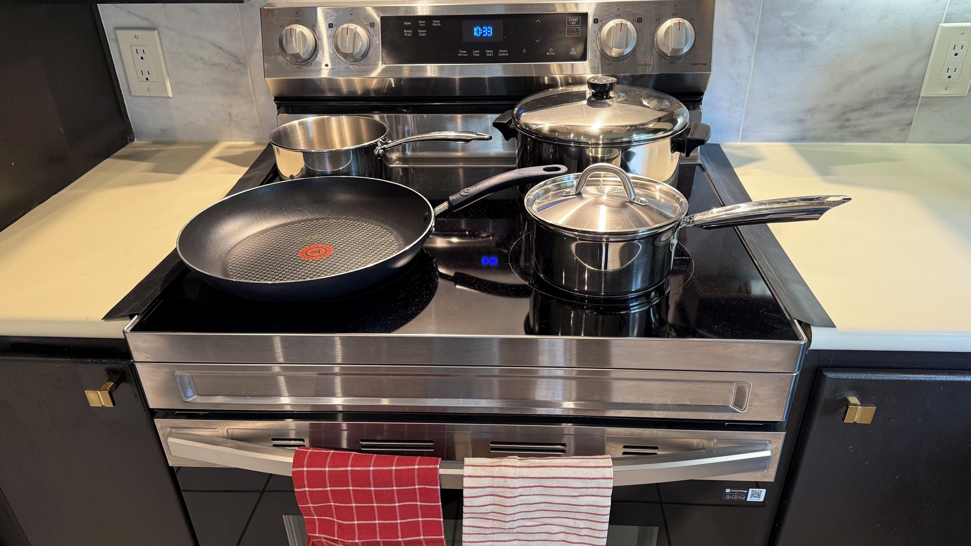 A kitchen with a stove, pots, and a frying pan.