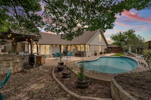 A backyard with a swimming pool, outdoor seating, and a stone wall.