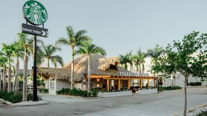 A Starbucks Coffee with a thatched roof, palm trees, and a drive-thru sign. - Cap Cana | Pool | Gym | Near Juanillo (Punta Cana)