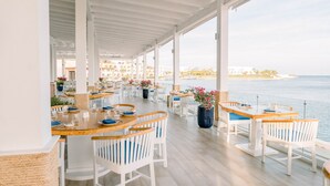 A covered outdoor dining area with tables and chairs, overlooking a body of water and a beach. - Cap Cana | Pool | Gym | Near Juanillo (Punta Cana)