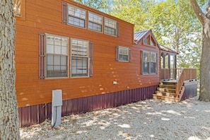 A two-story wooden house with a covered porch and a small staircase.