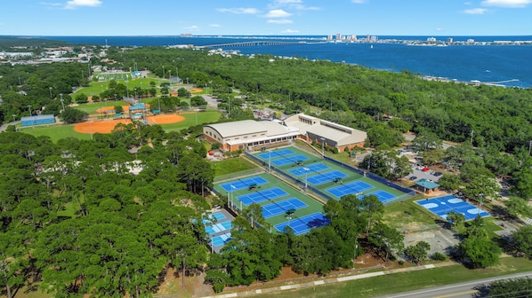 An aerial view of a sports complex with multiple tennis courts, a baseball field, and a large building. - Sunset on the Coast | Private Pool | Dog Friendly | Boat Launch | Volleyball & Pickleball (Gulf Breeze)