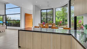 Een moderne keuken met een groot eiland, houten kasten en een eethoek met stoelen en een tafel.