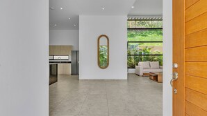 Een modern interieur met een keuken, een houten deur en uitzicht op groen.