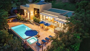 Een modern huis met een zwembad, buitenzitplaatsen en een groot raam.