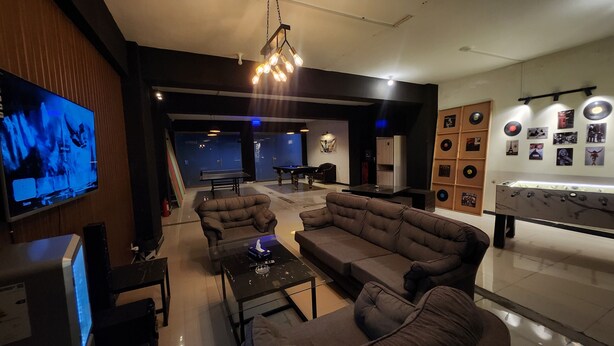 A modern lounge area with sofas, a pool table, a foosball table, and a wall of vinyl records.