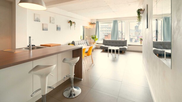 Een moderne keuken met een bar, een eethoek en een bank.
