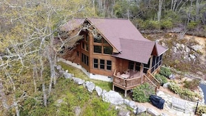Eine Blockhütte mit Veranda, umgeben von Bäumen und einer felsigen Landschaft.
