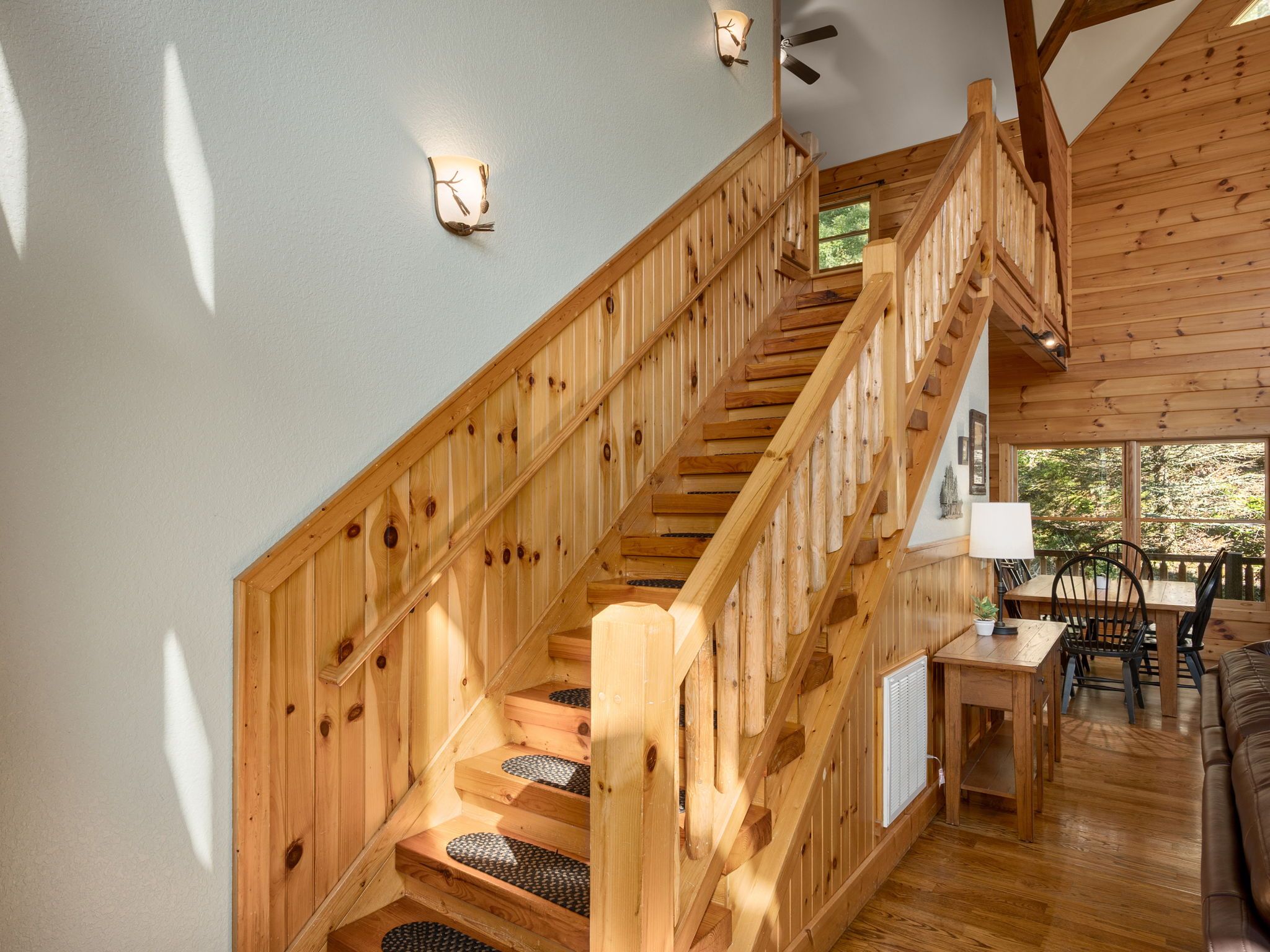 Eine Holztreppe mit Geländer, die zu einem Essbereich mit Tisch und Stühlen führt.