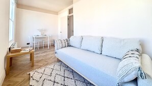 A modern living room with a sofa, a small table, and a chair. - Elegant Newly Renovated Apartment - Notting Hill (London)
