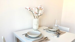 A white dining table with plates, glasses, and a vase of flowers. - Elegant Newly Renovated Apartment - Notting Hill (London)