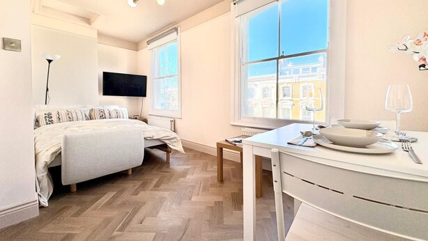 A modern bedroom with a bed, bedside table, and a large window. - Elegant Newly Renovated Apartment - Notting Hill (London)