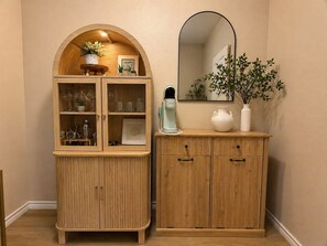 A wooden cabinet with glass doors, a mirror, and a small plant. - WPB142: Walk to the Beach, Pet Friendly, Rooftop Terrace (Port Aransas)