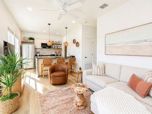 A modern kitchen with a refrigerator, stove, and hanging lights. - WPB142: Walk to the Beach, Pet Friendly, Rooftop Terrace (Port Aransas)