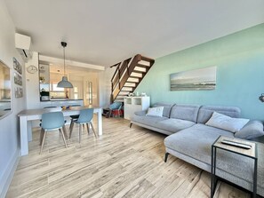 Ein zeitgemäßer Wohnbereich mit Essplatz, einer Couch und einer Treppe.