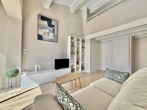 A modern living room with a sofa, a coffee table, a TV, a bookshelf, and a decorative plant. - CAP D'AGDE - Plage de la Roquille / Réf 0412 (CAP D'AGDE)