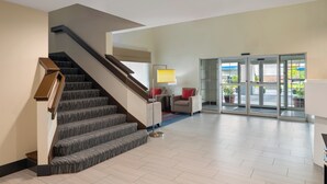 A modern lobby with a staircase, a seating area, and a glass door entrance.