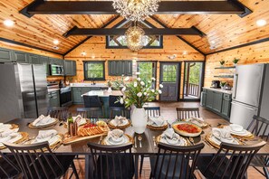 A spacious kitchen with wooden beams, a large island, and a dining area set for a meal.