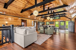 A spacious living area with a sofa, chairs, a dining table, and a kitchen in the background.