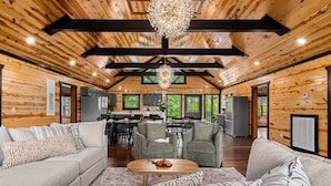 A spacious log cabin interior with a dining area, kitchen, and living room furnished with sofas and a coffee table. - 2 Bowling Lanes | 8BR Smoky Mtn Lodge | Hot Tub + 85° Pool + Arcade | Sleeps 22 (Sevierville)
