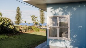 Una casa amb un petit jardí, una finestra amb cortines i vistes a l'oceà.