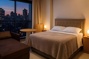 Een hotelkamer met een groot raam, een bed, een ronde tafel en een stoel.