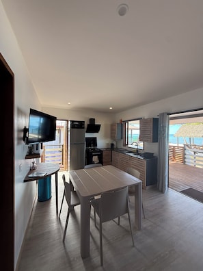 Una cocina moderna con televisor, mesa de comedor y sillas.