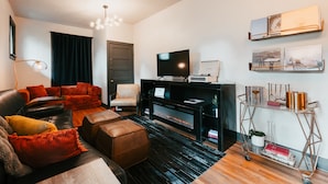 A modern living room with a fireplace, leather sofa, and a mounted television. - Swanky Speakeasy Stay-Hot Tub + Firepit-Minutes to Downtown (Moscow)
