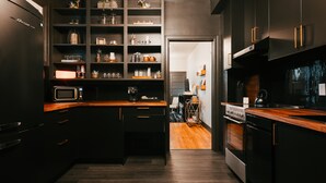 A modern kitchen with dark cabinetry, a wooden countertop, and a decorative ceiling. - Swanky Speakeasy Stay-Hot Tub + Firepit-Minutes to Downtown (Moscow)