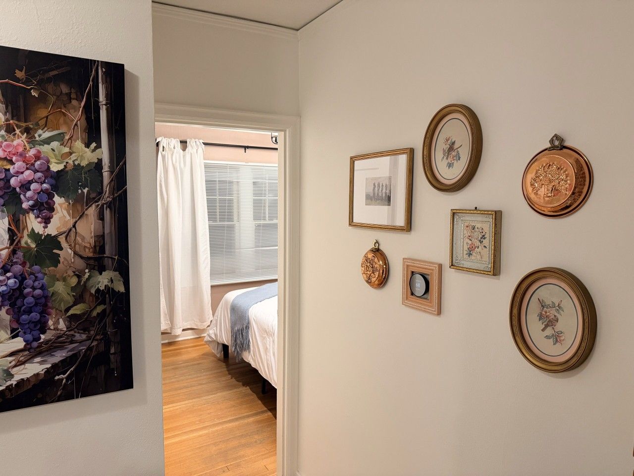 A bedroom with a bed, a window with curtains, and wall-mounted artwork.