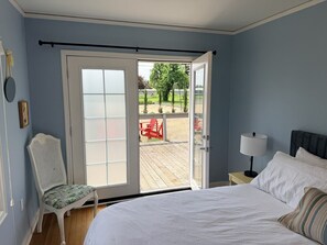 Een slaapkamer met een bed, een stoel, een nachtkastje en uitzicht op een terras.