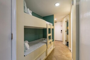 Ein Zimmer mit Etagenbetten, einem Badezimmer mit Spiegel und einer Tür zu einem weiteren Raum.