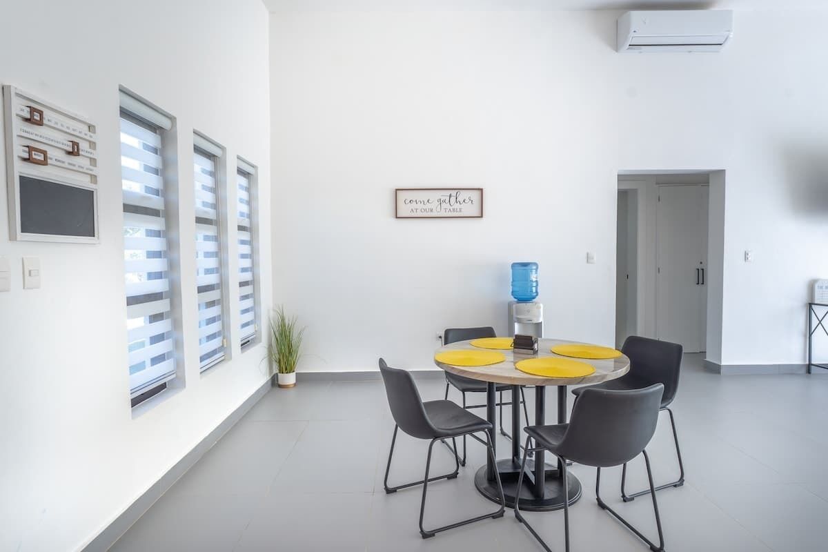 Un espace repas moderne avec une table ronde, quatre chaises et un climatiseur fixé au mur.