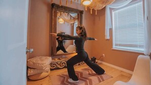 A room with a large mirror, a white chair, a patterned rug, and a door. - ZenDen Spa+Sauna+Hot Tub+Pet Friendly+No Pet Fee! (Albuquerque)