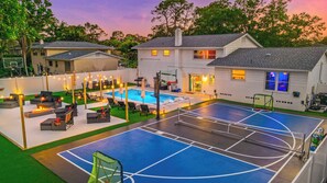 Ein Wohnhaus mit Swimmingpool, Sitzgelegenheiten im Freien und einem Basketballplatz.