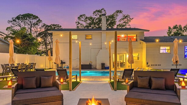 A poolside area with wicker sofas, a fire pit, and string lights. - GAME ON! Heated Pool, Pickleball, Outdoor Theater! (Seminole)