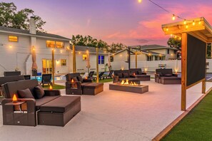 Ein Patio mit Gartenmöbeln, einem Feuerkorb und Lichterketten.