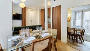 Un'area pranzo moderna con un tavolo in vetro, sedie in legno e un divano verde.
