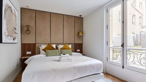 Una camera da letto con un letto grande, una testiera in legno e vista all'esterno attraverso una finestra.