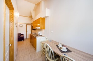A compact kitchen with wooden cabinets, a dining table with chairs, and a small seating area with a sofa. - Beachfront Apartment Mareo 6 (Nin)