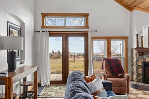 Ein gemütliches Wohnzimmer mit Sofa, Couchtisch, Kamin und Blick ins Freie.