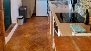 Een keuken met houten balken, een kleine koelkast, een spoelbak en een betegelde achterwand.
