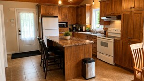 Una cocina con armarios de madera, una isla central, un refrigerador, un microondas, un horno y un lavamanos.